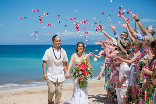 Small wedding group tossing flowers on a Maui beach